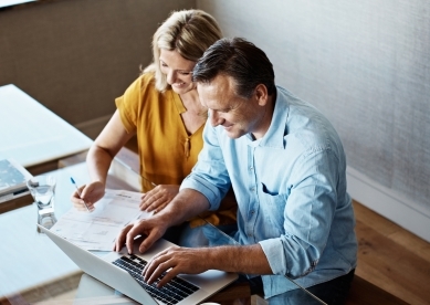 Couple sitting at table with computer and financial documents